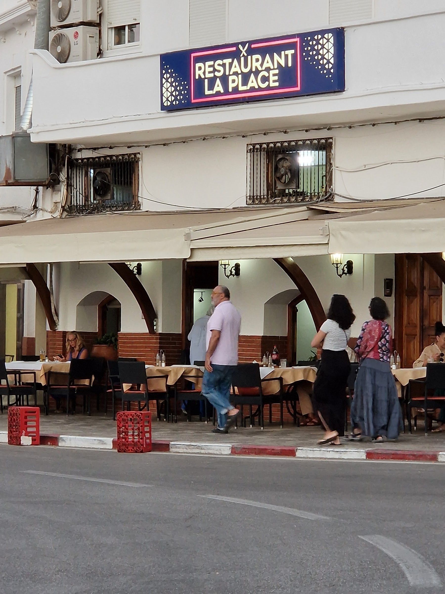 Passants et terrasse de La Place un jour de soleil
